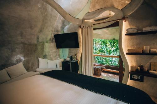 a bedroom with a bed with a large window at Orchid House Tulum Jungle in Tulum