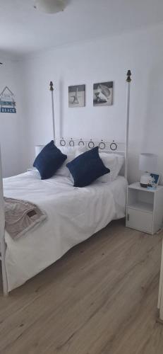 a bedroom with a large white bed with blue pillows at Serendip@sea in Cape Town