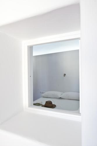 a mirror reflecting a bed with a hat on it at Villa Varnali Small Boutique in Mikonos