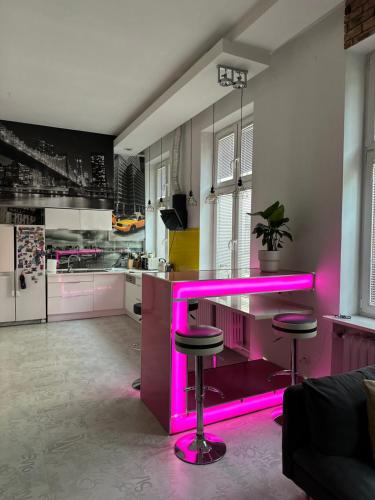 una cucina con bancone rosa con sgabelli di P-122 Piotrkowska Apartment. a Łódź