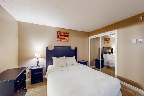 a bedroom with a large white bed and a mirror at Condo 503 at North Creek Resort in Blue Mountains