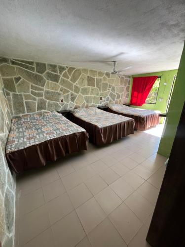 a room with two beds and a stone wall at Hotel Villa Aventura in Cuetzalán del Progreso