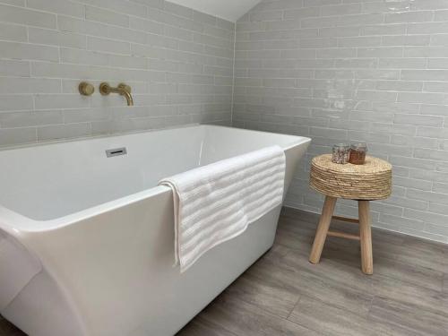 a white bath tub in a bathroom with a stool at No.8 Laura Place in Aberystwyth