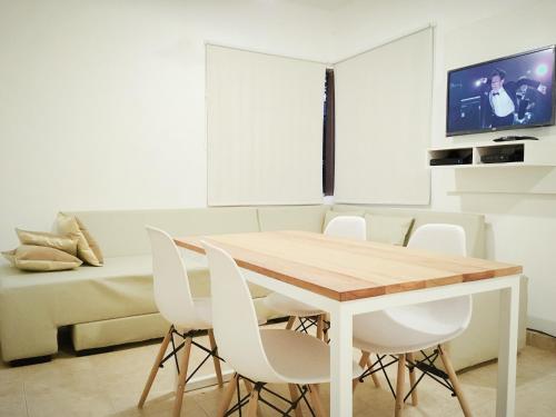 a dining room with a wooden table and white chairs at AMSTERDAM DEPARTAMENTOS in Villa Carlos Paz