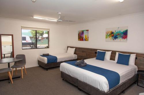 a bedroom with two beds and a desk and a table at Matilda Motor Inn in Dubbo