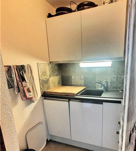 une petite cuisine avec des armoires blanches et un évier dans l'établissement Résidence Lunik - Appartement rénové · Pied des pistes · Balcon MAE-9381, à Villarembert