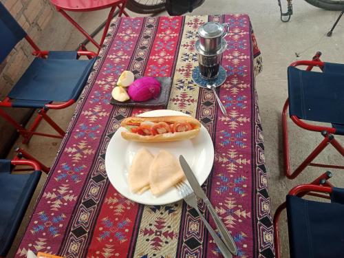 a table with a plate with a sandwich and a knife at Ha Giang Yolo House and Loop Tours in Ha Giang