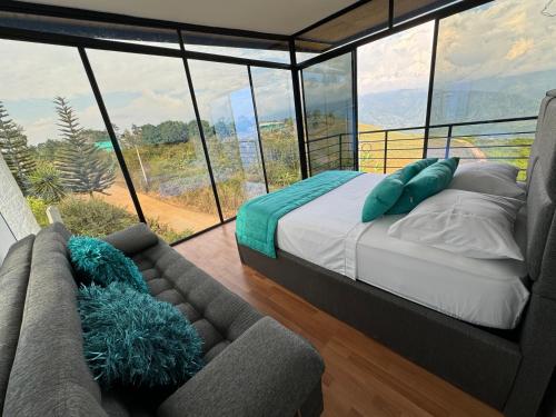 ein Schlafzimmer mit einem Bett und einem Sofa vor einem Fenster in der Unterkunft Se Alquila Hermosa Cabaña Turquesa in Lebrija
