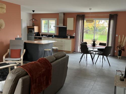 een woonkamer en een keuken met een bank en een tafel bij LA VREMONTOISE in Mâcon