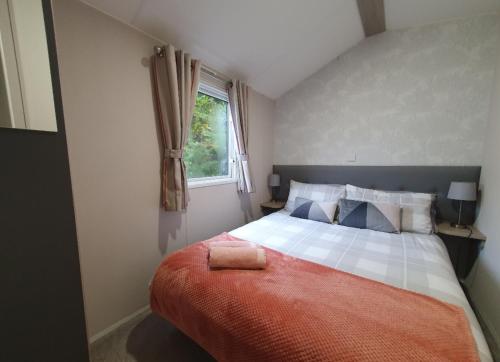 een slaapkamer met een bed met een rode deken en een raam bij Percy Wood Getaway Hot Tub in Swarland