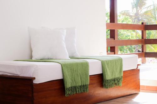 a bedroom with a bed with a green blanket on it at Pousada Morada do Sol in Jericoacoara