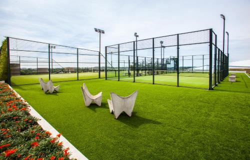a tennis court with three white chairs on the grass at Hotel Pullman City Center Rosario in Rosario