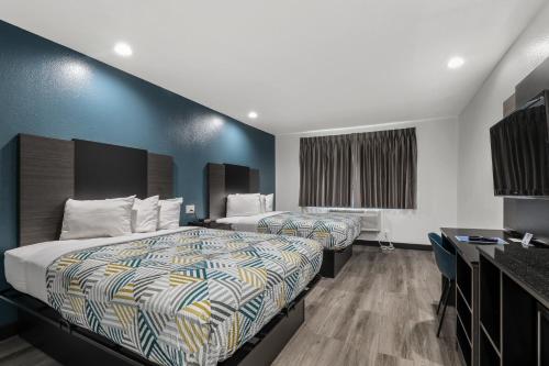 two beds in a hotel room with blue walls at Studio 6 Suites Perris, CA in Perris