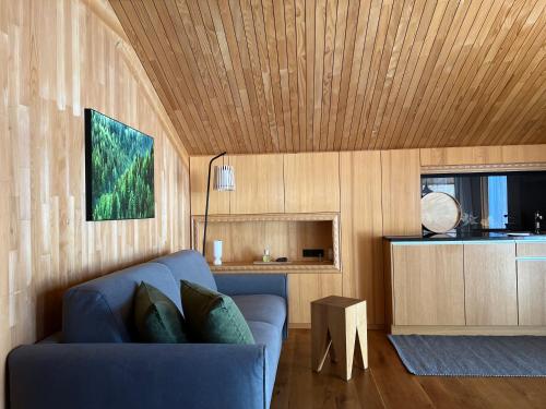 a living room with a blue couch and wooden ceiling at Naturhaus Loacker in Lech am Arlberg