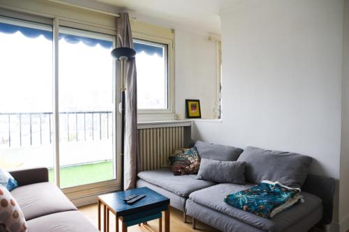 un salon avec un canapé et une grande fenêtre dans l'établissement 50 m unoverlooked nest with Eiffel Tower view, à Paris