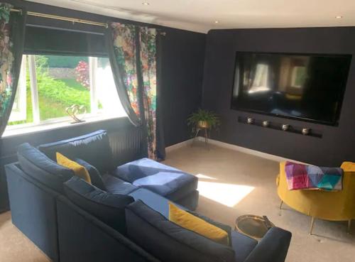 a living room with a blue couch and a tv at The Annexe at Greendyke House in Addingham