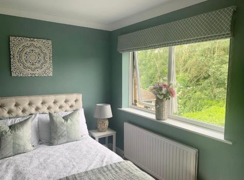 Schlafzimmer mit blauen Wänden, einem Bett und einem Fenster in der Unterkunft The Annexe at Greendyke House in Addingham