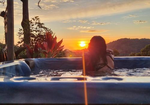 una mujer sentada en una bañera con la puesta de sol en el fondo en The House of the Rising Sun, en Tallebudgera