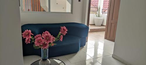 a vase with pink flowers on a table next to a blue couch at Hotel Mykonos Manta in Manta