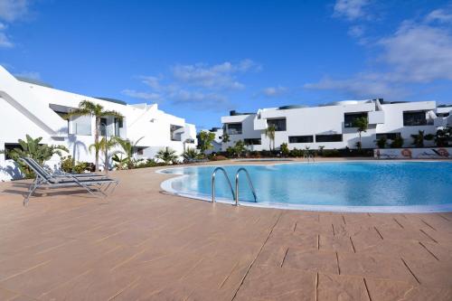 a swimming pool in front of some white buildings at Luxury Apartment in Casilla de Costa - Casa MEVA in Lajares