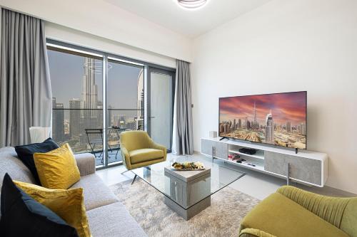 a living room with a couch and a tv at SmartStay at Burj Royale - Full Burj Khalifa View - Brand New Luxury Apartments in Dubai