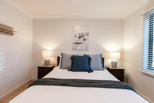 a white bedroom with a bed with two night stands at Ocean Grace by the River and Ocean Pet Friendly in Ocean Grove