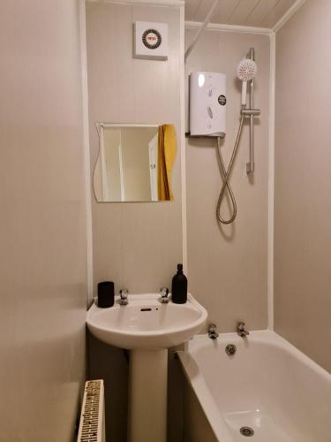 a white bathroom with a sink and a bath tub at Cathcart Place Rooms in Edinburgh