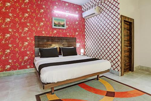 1 dormitorio con cama y pared roja en Super Collection O Hotel Bhinna Sakala, en Bhubaneshwar