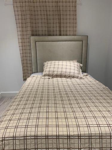 a bed with a plaid comforter and a pillow at stranmillis Suites in Belfast