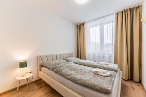 - une chambre avec un grand lit et une fenêtre dans l'établissement Apartmán Troika, à Liptovský Hrádok