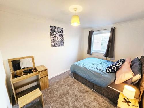 a bedroom with a bed and a desk and a television at Whitefield, Manchester in Manchester