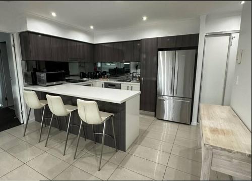 a kitchen with a large white counter and stools at New Farm 2 Bed 2 Bath 1 Car space perfect location in Brisbane