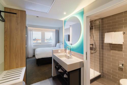 ein Bad mit einem Waschbecken, einem Bett und einem Spiegel in der Unterkunft Holiday Inn Express Dresden Zentrum, an IHG Hotel in Dresden
