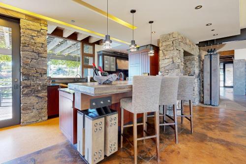 cocina con pared de piedra y barra con taburetes en Gustafson Vineyard Retreat en Geyserville