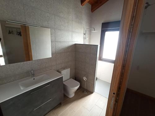 a bathroom with a toilet and a sink and a mirror at La finca del Goño in Pravia