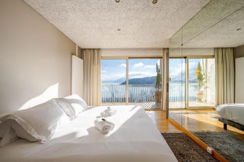 une chambre avec un lit blanc et une grande fenêtre dans l'établissement Le Panoramic - Magnifique Vue sur le lac d'Annecy, à Annecy