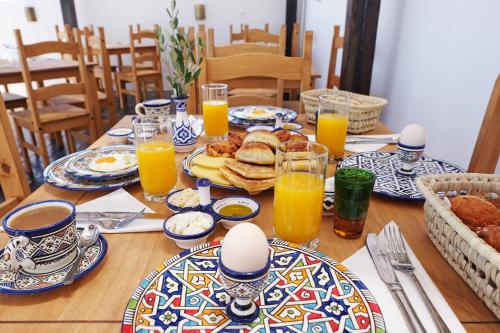 a table with plates of food and glasses of orange juice at Riad Alassala Fes in Fès