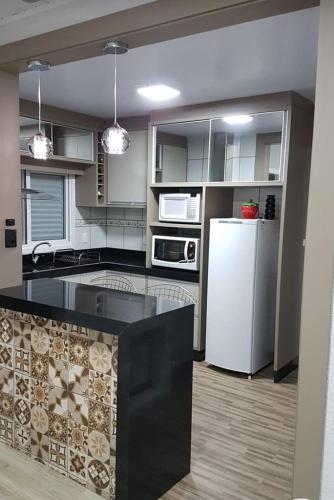 uma cozinha com um balcão preto e um frigorífico branco em recanto do aconchego em Contagem