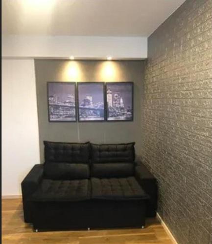 um sofá preto num quarto com uma parede de tijolos em recanto do aconchego em Contagem