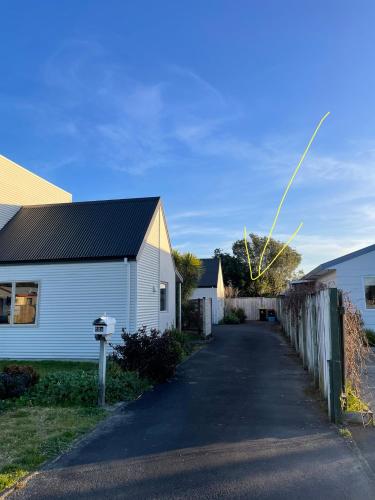 a white house with a fence and a driveway at Papamoa Two Rooms & Kitchenette - Dogs welcome in Papamoa