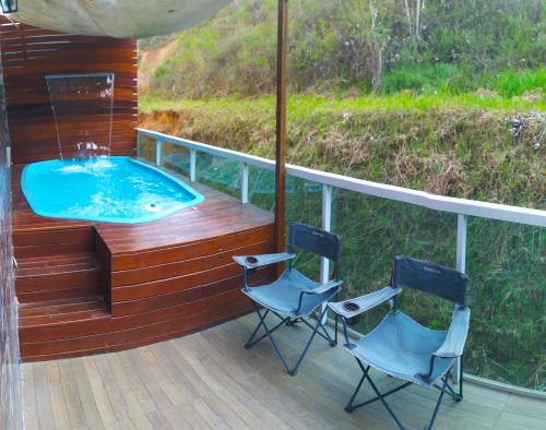 twee stoelen en een hot tub op een terras bij Apartamento com vista para piscina in Cataguases