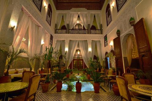 una grande stanza con tavoli, sedie e piante di Riad Alassala Fes a Fes