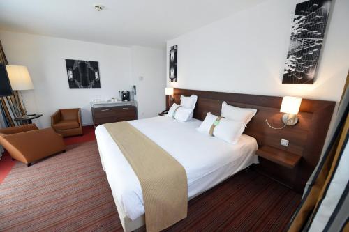 a hotel room with a large bed and a chair at Holiday Inn Mulhouse by IHG in Mulhouse