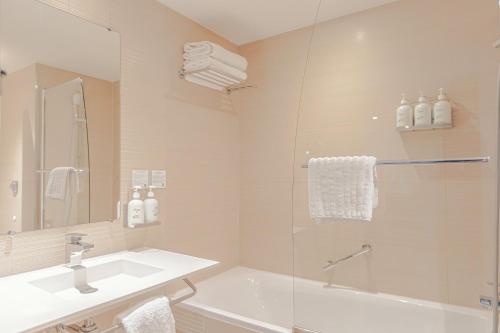 a bathroom with a shower and a sink and a tub at Holiday Inn Mulhouse by IHG in Mulhouse
