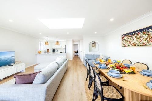 a living room with a long table and a couch at Bel Air, 8A Ocean Ave - pet friendly, water views and air con in Anna Bay