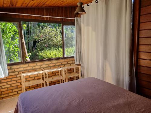 a bedroom with a bed and two chairs and a window at Casa 4 dorms 2 suites - localização perfeita no centrinho e rodeada de natureza in Alto Paraíso de Goiás