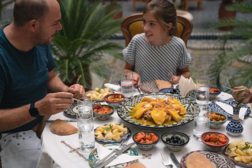 a man and woman sitting at a table with food at Riad Alassala Fes in Fès