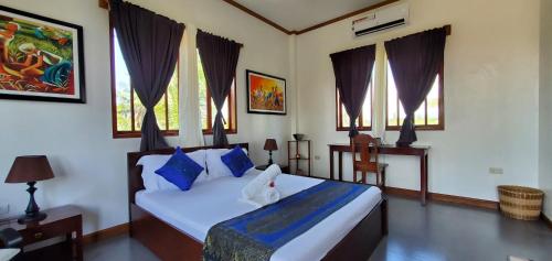 a bedroom with a bed with blue pillows and windows at Palmera Palma Top Floor in Moalboal
