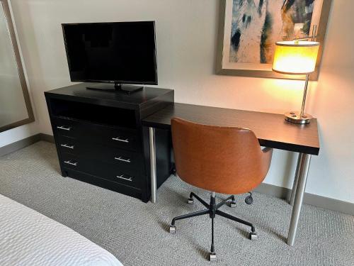 a bedroom with a desk with a television and a chair at Holiday Inn Carlsbad/San Diego by IHG in Carlsbad