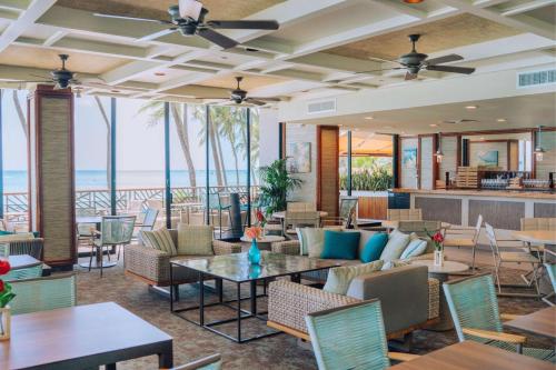 eine Lobby mit Tischen und Stühlen und der Strand in der Unterkunft OUTRIGGER Waikiki Beach Resort in Honolulu